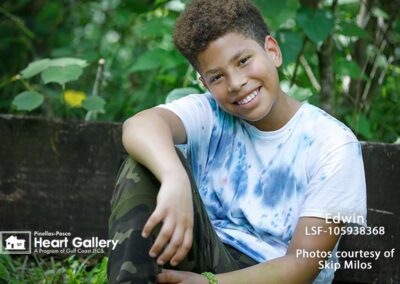 A boy with a tie-dye shirt in front of greenery